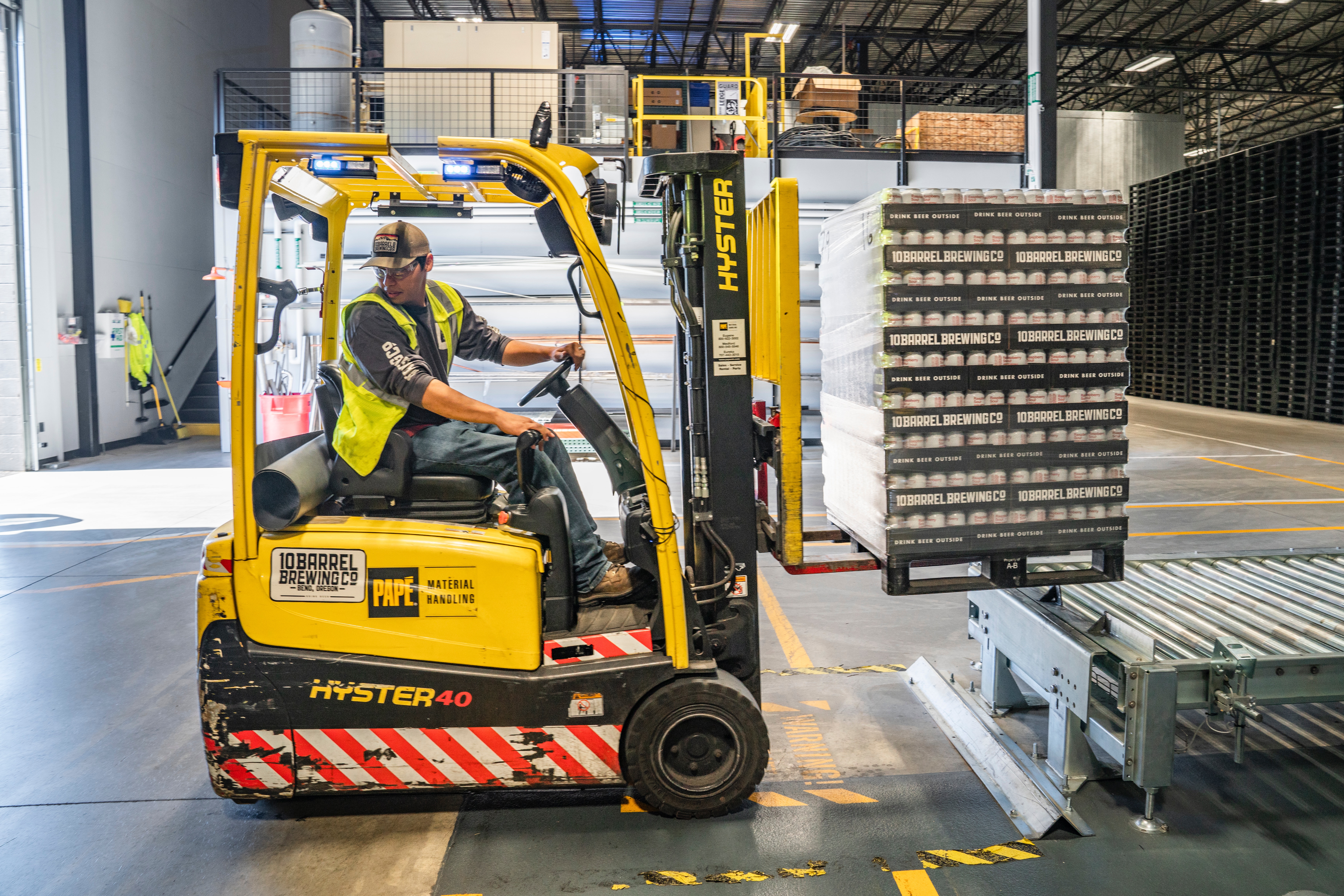 Man using a pallet lifter in the external part of the theatre to move stock for the theatre bar.