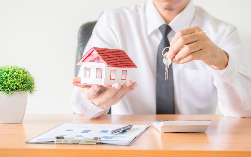 man in shirt and tie holding model of house and house keys